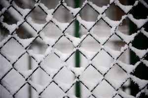 A security fence covered in snow during winter